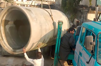Crane loading an RCC pipe onto a delivery truck
